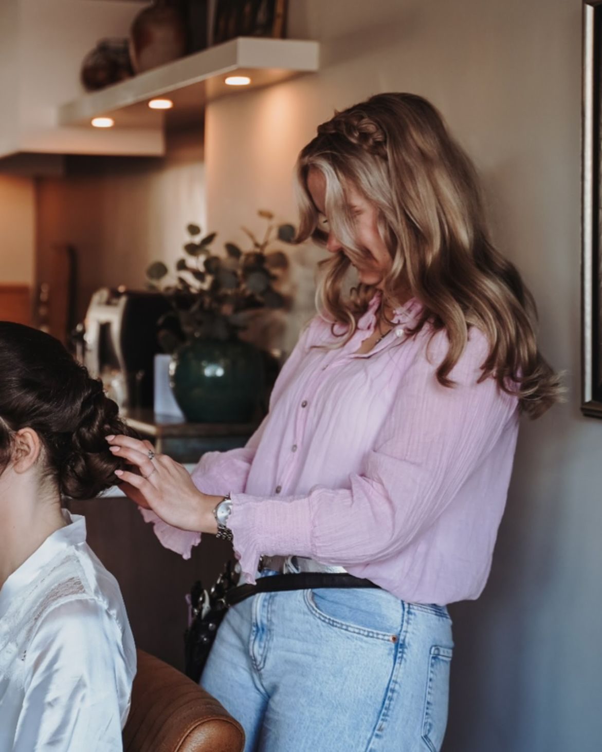 Luca werkt aan het opgestoken haar van een klant in een witte kimono